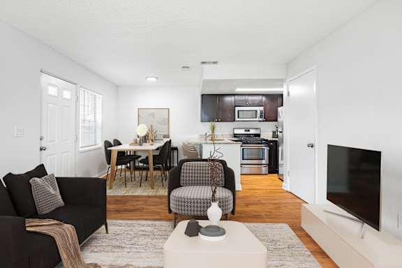 A black couch with a brown throw blanket on it sits in a living room.