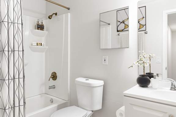 A white bathroom with a toilet, sink, and mirror.
