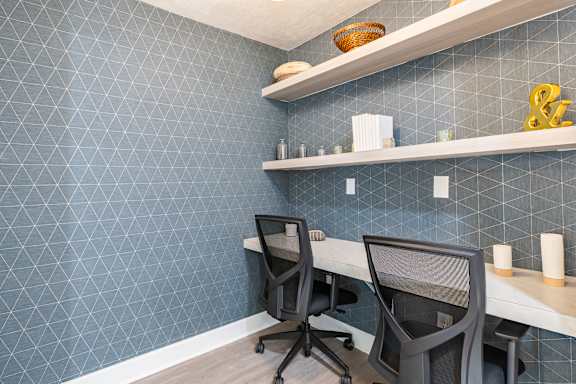 Two black chairs are in front of a desk with a computer.