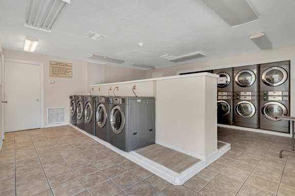 A laundry room with washing machines and a bench.