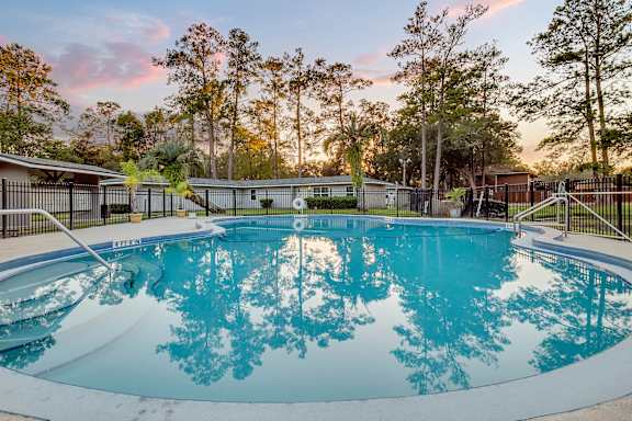 A swimming pool surrounded by a fence and trees.