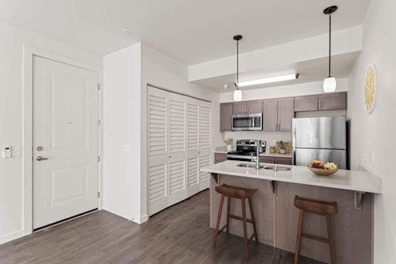 A kitchen with a white counter and brown stools.