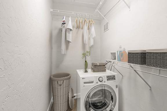 A laundry room with a washing machine and clothes hanging up.