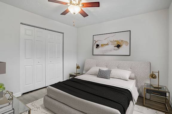 A bedroom with a bed, nightstand, and a painting on the wall.