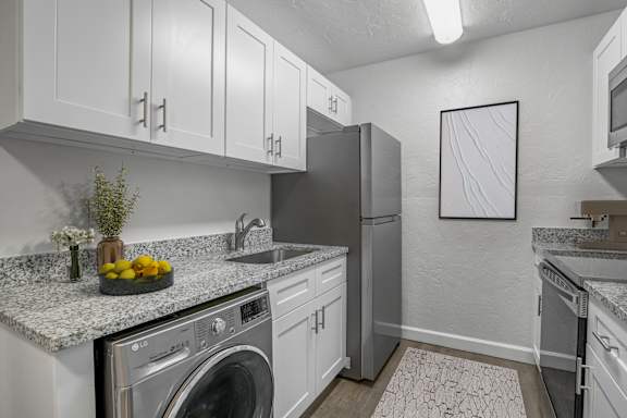 A modern kitchen with granite countertops and stainless steel appliances.