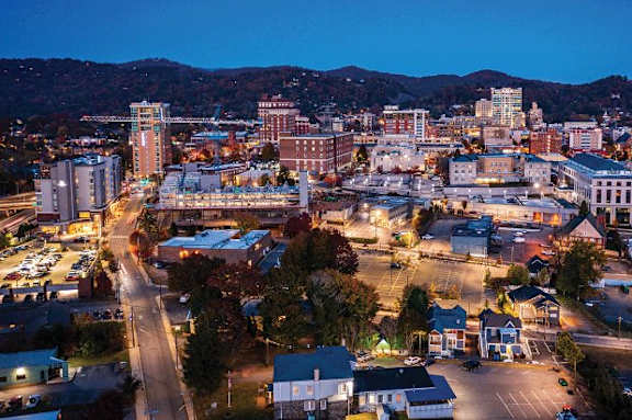 A cityscape at dusk with buildings and streets illuminated.