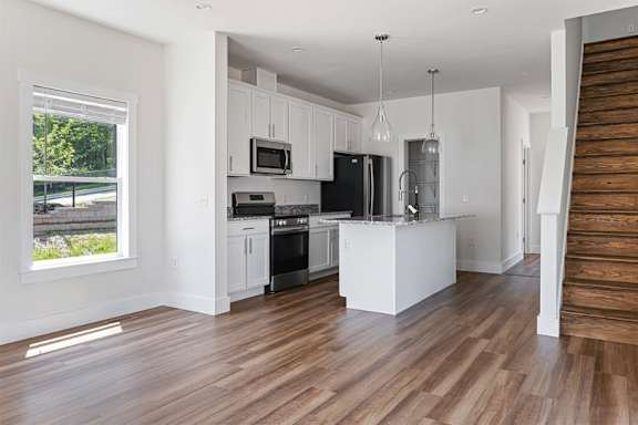 A kitchen with white cabinets and a wooden floor.