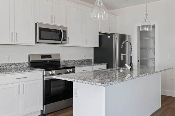 A kitchen with white cabinets and granite countertops.