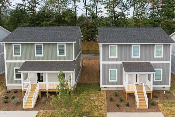 Two houses with grey siding and white trim are shown from an aerial perspective.