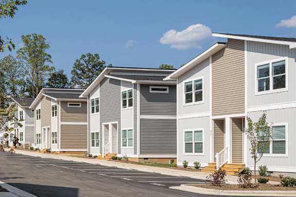 A row of modern townhouses with a clear blue sky above them.