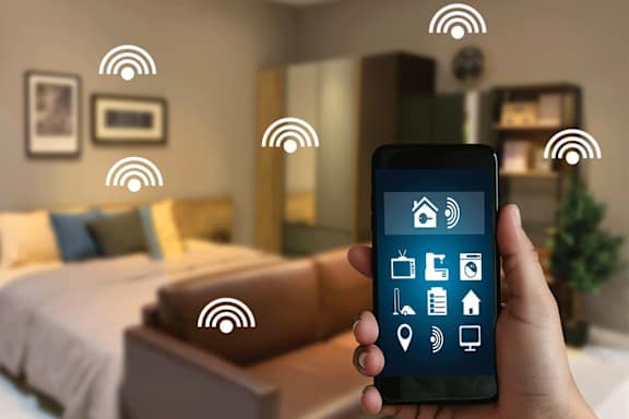 A hand holding a smartphone with Wi-Fi symbols floating around it.