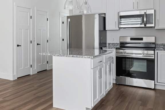 A kitchen with white cabinets and a granite countertop.