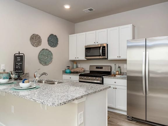 A kitchen with a granite countertop and stainless steel appliances.