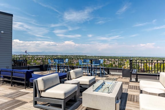a rooftop deck with couches and tables and a view of the city
