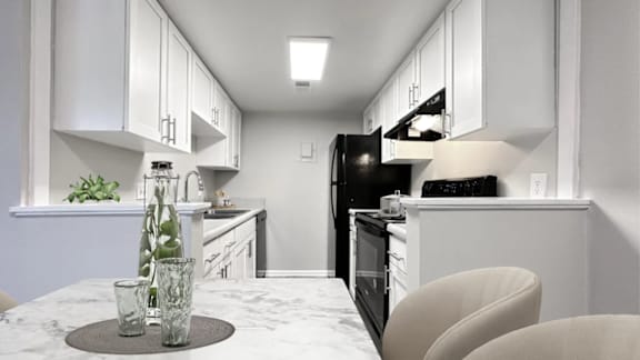 A modern kitchen with white cabinets and black appliances.
