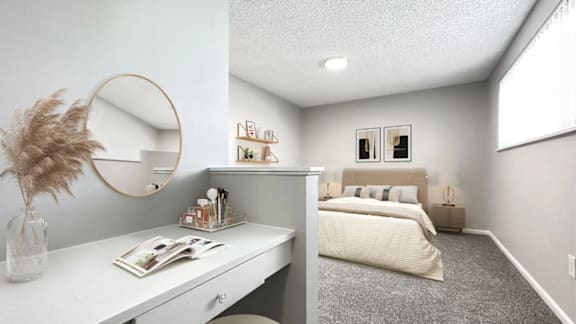A bedroom with a bed, nightstand, and a vanity with a mirror.