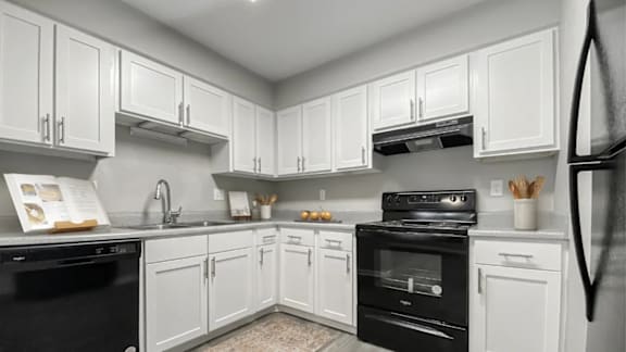 A kitchen with white cabinets and black appliances.