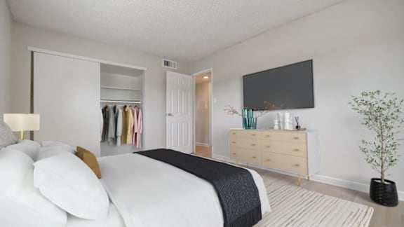 A bedroom with a large bed, a TV, and a wardrobe.