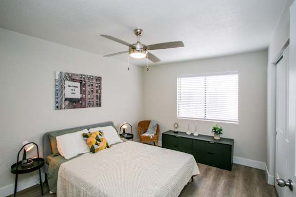 A bedroom with a bed, nightstand, and a ceiling fan.