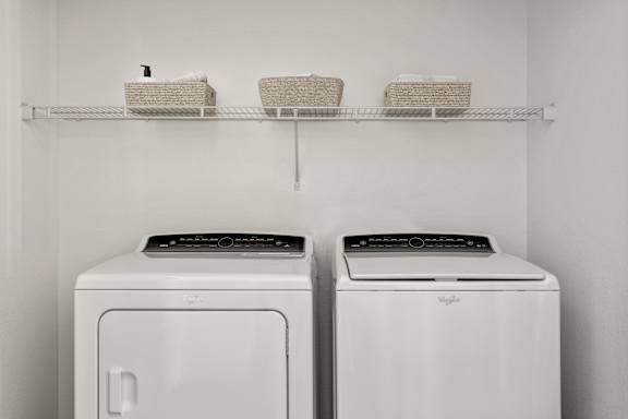 Two white front loading washing machines in a laundry room.