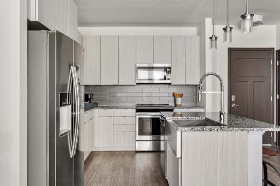 A modern kitchen with a refrigerator, sink, and stove.