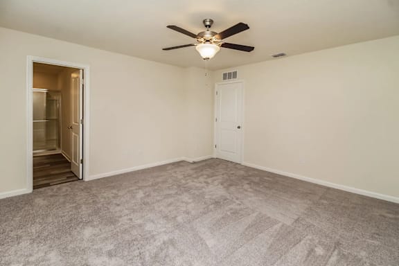 A room with a ceiling fan and carpeted floor.