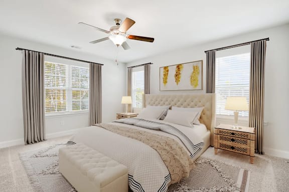 A bedroom with a large bed, a ceiling fan, and a rug on the floor.