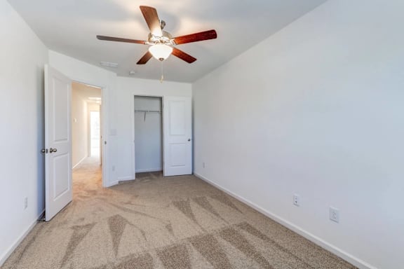 A room with a ceiling fan and carpeted floor.