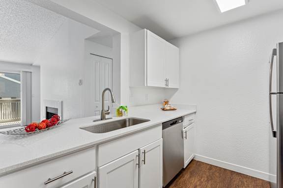 A kitchen with white cabinets and a stainless steel refrigerator.