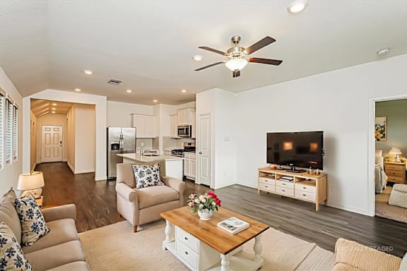 A living room with a ceiling fan and a flat screen TV.