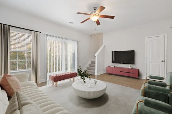 A living room with a white couch, a red bench, a white coffee table, and a ceiling fan.