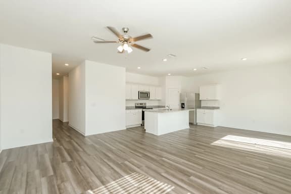 A spacious kitchen and living room with a ceiling fan and lighting.