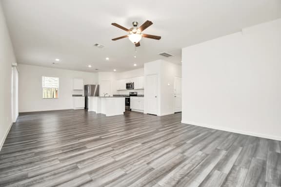 A spacious room with a ceiling fan and wooden flooring.