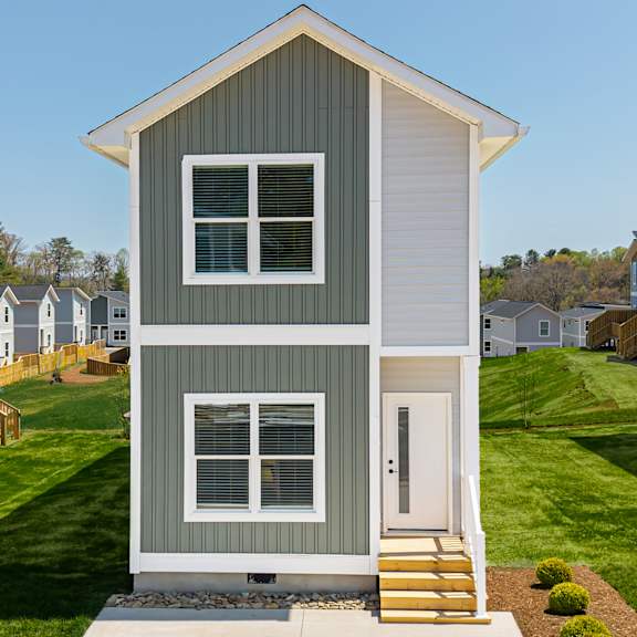 A small house with a grey and white exterior and a white door.