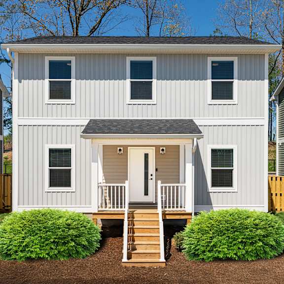 A white house with a grey roof and a front porch.