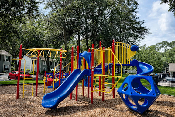 A playground with a blue slide and yellow and red play equipment.