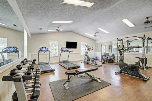 A spacious gym with a variety of equipment including treadmills, stationary bikes, and weight machines.