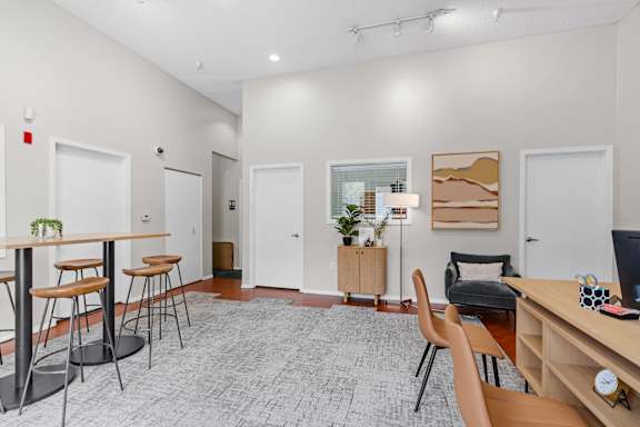 A room with a desk, chairs, and a potted plant.