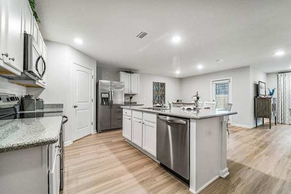 A kitchen with white cabinets and a granite countertop.