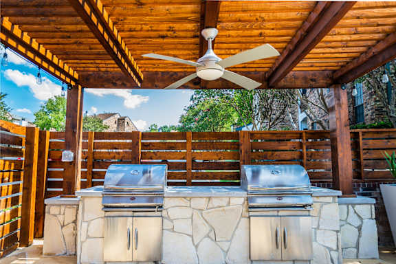 an outdoor kitchen with stainless steel appliances and a wooden roof