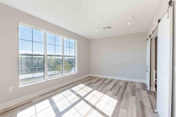 A sunny room with a large window and wooden flooring.