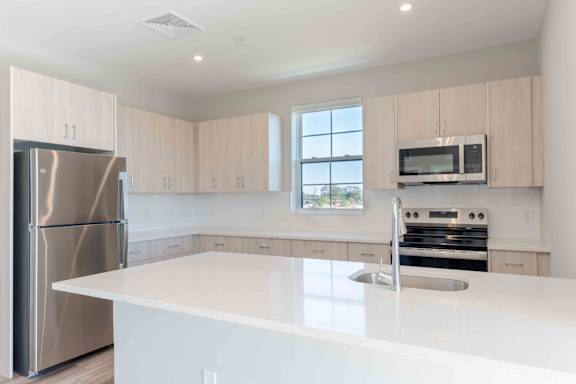 A modern kitchen with a stainless steel refrigerator and white countertops.