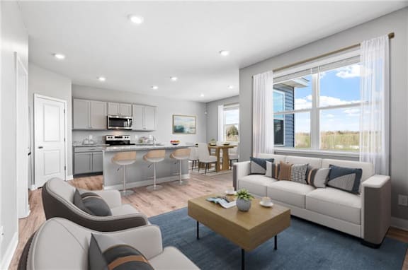 A modern living room with a kitchen area in the background.