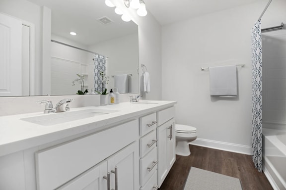 A white bathroom with a sink, toilet, and shower.