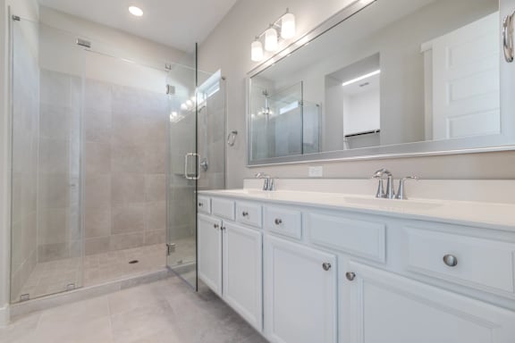 A bathroom with a walk-in shower, double sinks, and a large mirror.