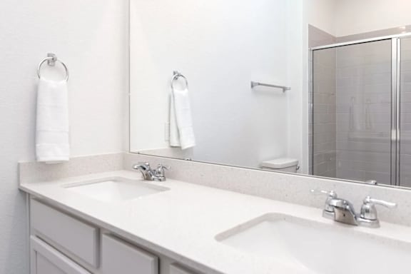 A white bathroom with a sink and mirror.