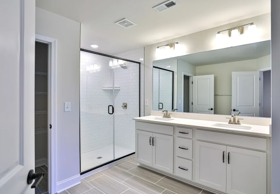 A bathroom with a walk-in shower and double sinks.