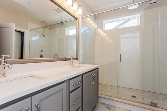 A bathroom with a sink, mirror, and shower.