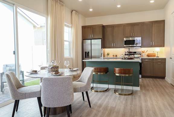 A modern kitchen with a dining table set for two.