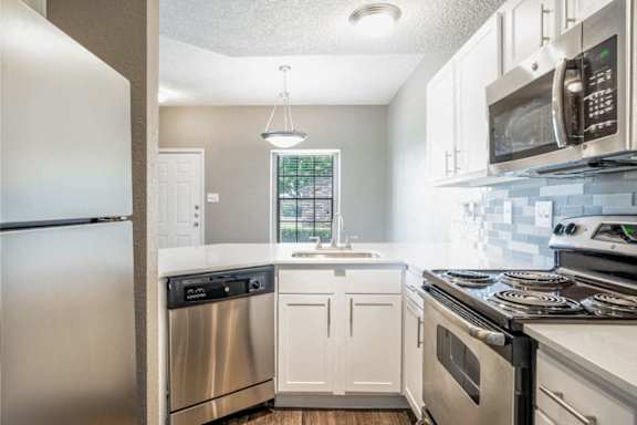 A kitchen with a stainless steel refrigerator, dishwasher, and oven.